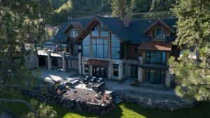 Large modern cabin in wooded hillside setting.