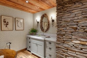 Rustic bathroom with stone wall and wood accents.