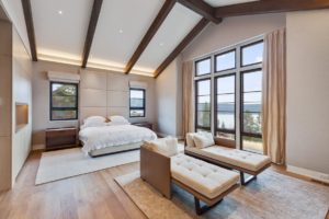 Luxury bedroom with lake view and wooden beams.