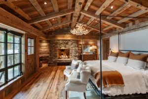 Rustic bedroom with fireplace and wooden beams.