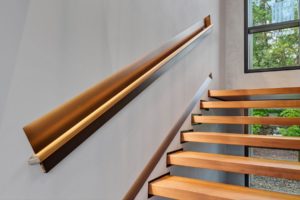 Modern wooden stairs with sleek handrail design.