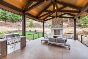 Outdoor patio with grill and stone fireplace.