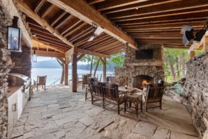 Rustic lakeside patio with fireplace and seating