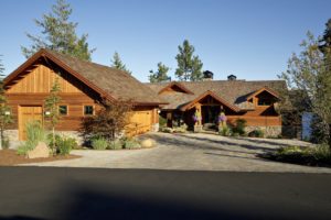 Rustic wooden cabin with stone details and driveway.
