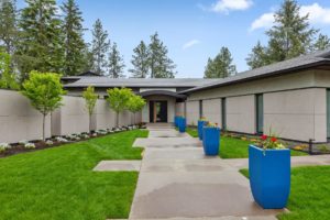 Modern home entrance with blue planters and green lawn.