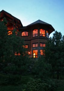 Wooden house at dusk surrounded by trees.