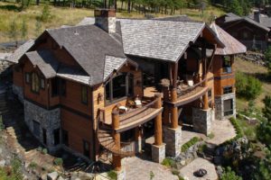 Rustic wooden house with balcony in forest setting.