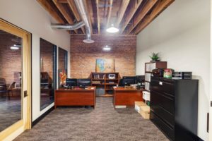 Modern office with brick walls and wooden desks.