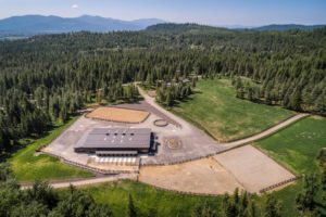 Aerial view of farm surrounded by lush green forest.