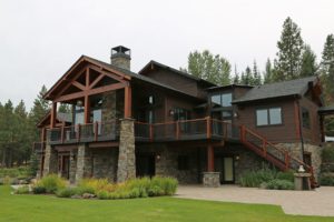 Rustic cabin with stone and wood accents in forest setting.