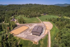 Aerial view of equestrian center in forest setting.
