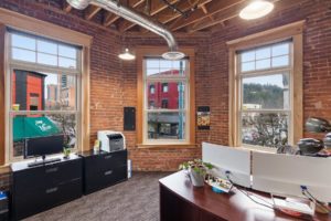 Modern brick office with large windows and desk.