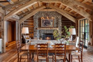 Rustic cozy living room with fireplace and wooden ceiling.