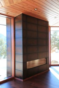 Lake Fernan Residence - Passive House Institute Certified Modern fireplace in wooden cabin interior design.