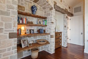 Rustic shelf with books and family photos on stone wall.