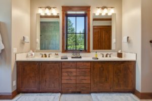 Wooden bathroom vanity with mirror and window view.
