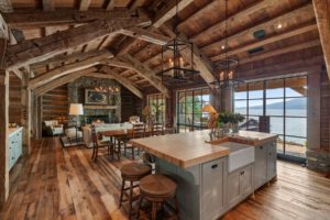Rustic lakeside interior with wooden beams and fireplace.