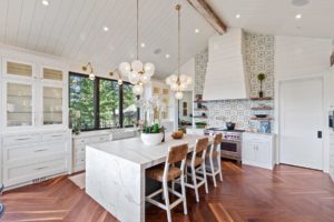 Modern white kitchen with island and pendant lights.