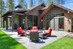 Rural home patio with red furniture and lush greenery.