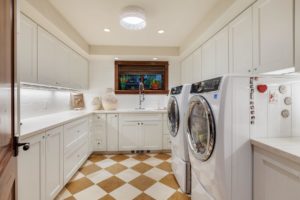 Hayden Lake Chalet Modern laundry room with white cabinets and appliances.
