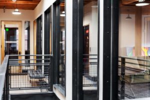 Modern office hallway with glass walls and metal rails.