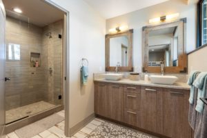 Modern bathroom with double sinks and glass shower.