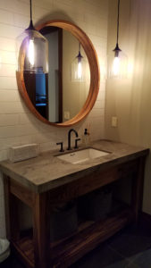 Modern bathroom vanity with round mirror and lights.