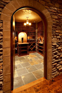 Elegant home wine cellar with stone walls and wood racks.