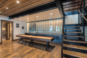 Modern game room with wood and metal staircase.
