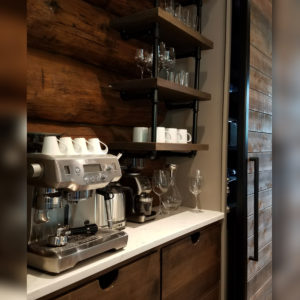 Home coffee station with espresso maker and shelves.