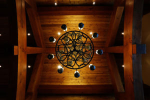 Rustic metal chandelier on wooden ceiling.