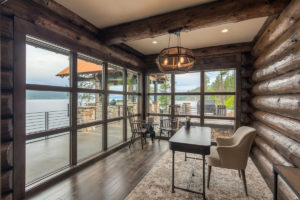 Rustic lakeside study with large windows.