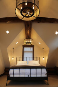 Cozy attic bedroom with modern lighting fixtures.