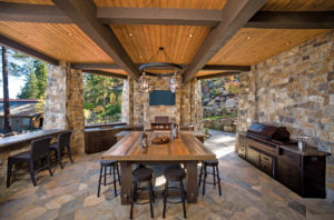 Outdoor stone kitchen with grill and wooden table.