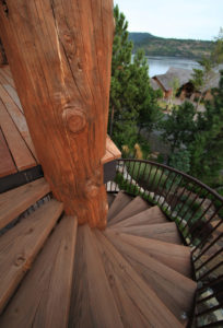 Spiral wooden staircase with scenic forest view.