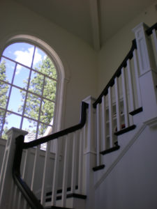Elegant white staircase with large arched window.