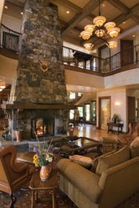 Rustic living room with stone fireplace and high ceiling.