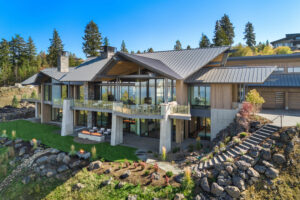 Modern lakefront luxury home with large windows and balcony.