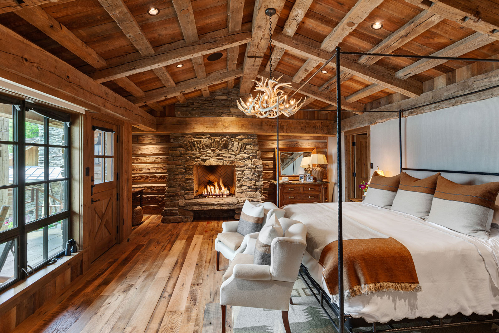 Cozy rustic bedroom with stone fireplace and wooden beams.