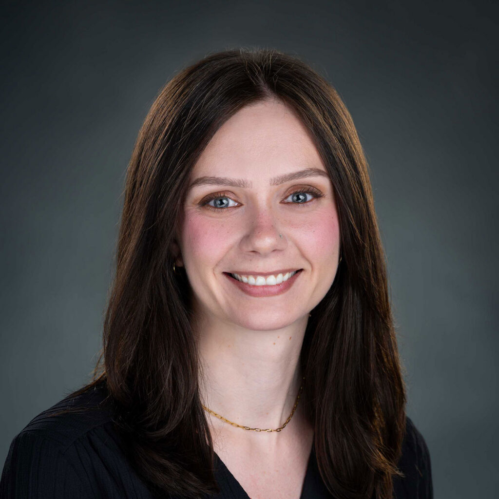 Smiling woman with long dark hair and blue eyes.