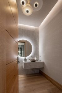 Black Rock Residence #7 Powder room with a backlit round mirror and floating natural stone vanity