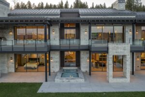 Rear elevation of Black Rock Residence #7 at dusk showing stacked covered patios, glass railings and a sunken spa