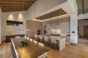 Black Rock Residence #7 Kitchen and dining area with oak flooring, linear pendant lighting and a live-edge dining table