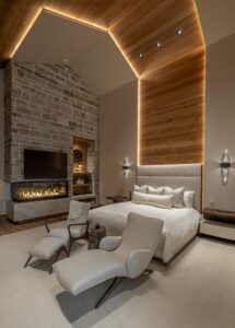 Black Rock Residence #7 Primary bedroom with a linear fireplace, stone surround and wood-clad vaulted ceiling