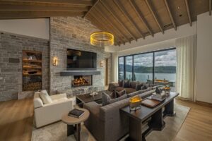 Black Rock Residence #7 Great room with a full-height stone fireplace, timber ceiling and floor-to-ceiling glass overlooking the lake